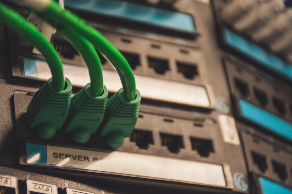 pexels-photo-1597776 Close-up of green network cables plugged into server ports, showcasing technology setup.